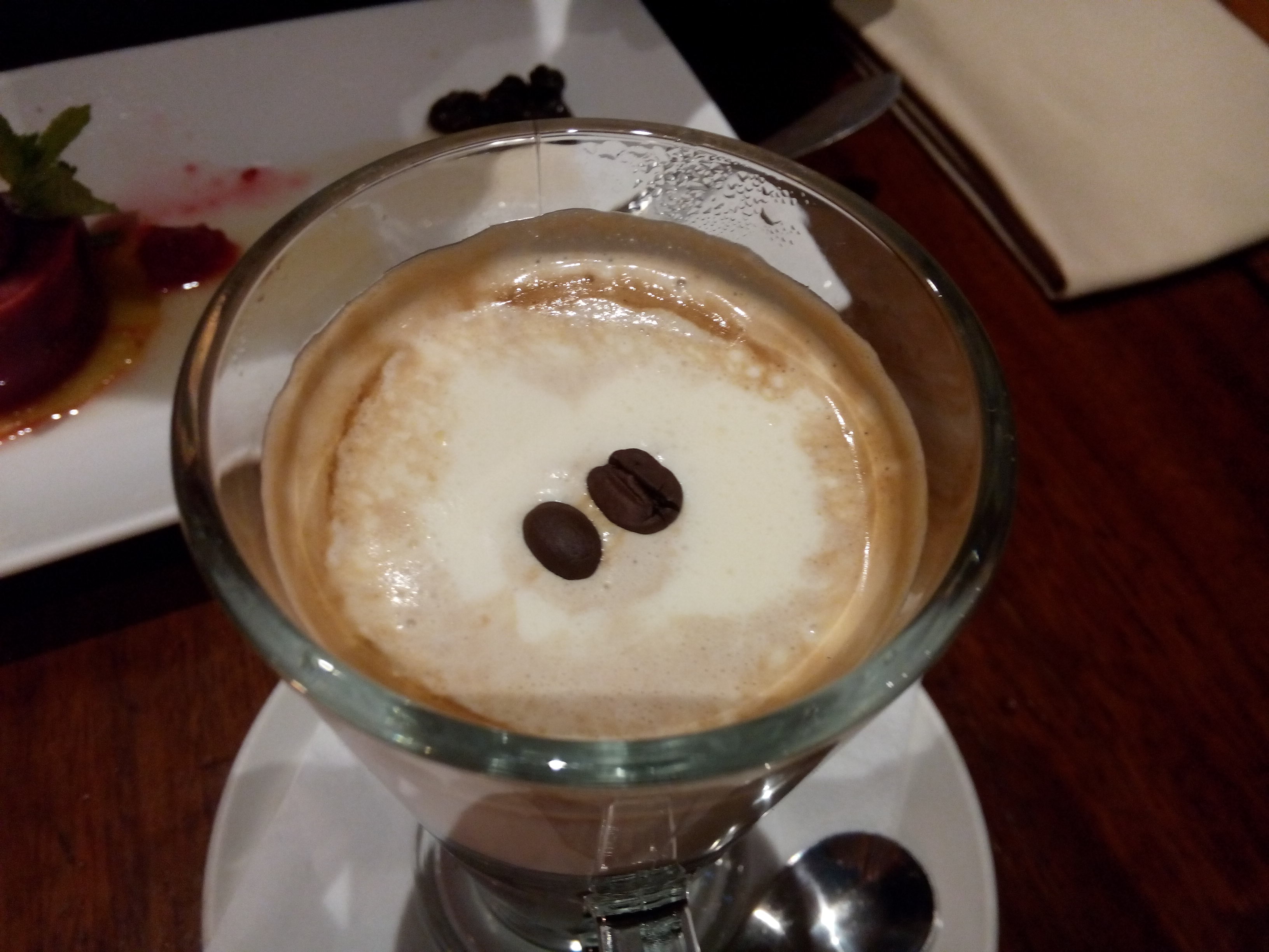 A foamy coffee with two coffee beans on top