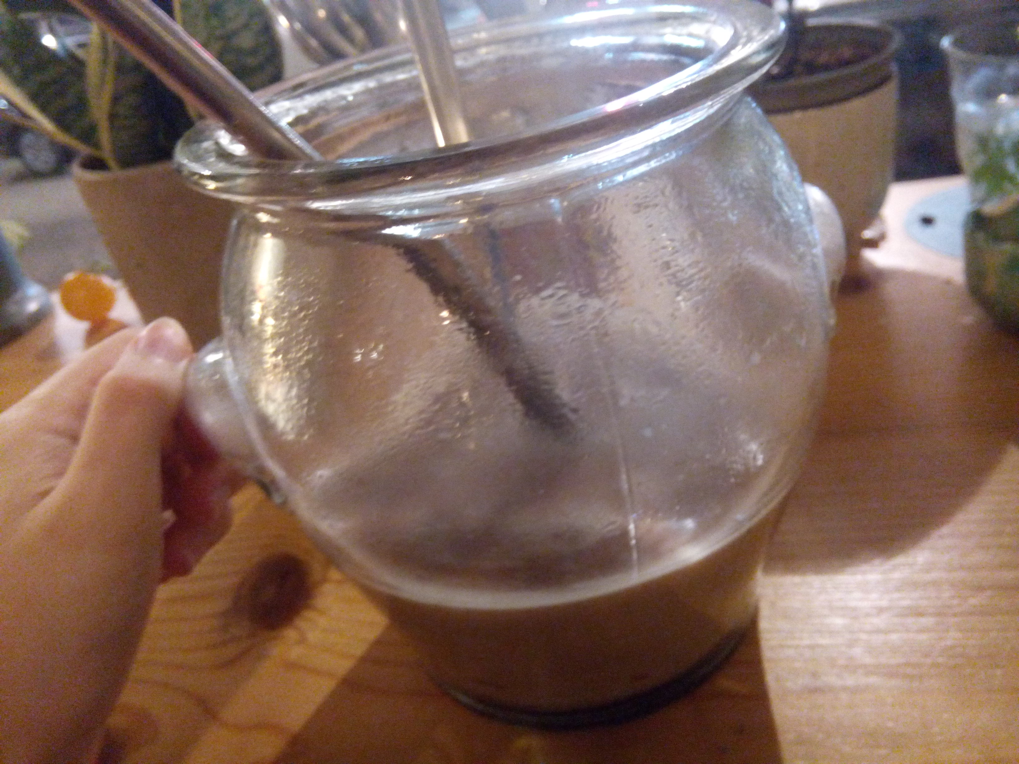 A hot chocolate served in a large vase with a metal straw