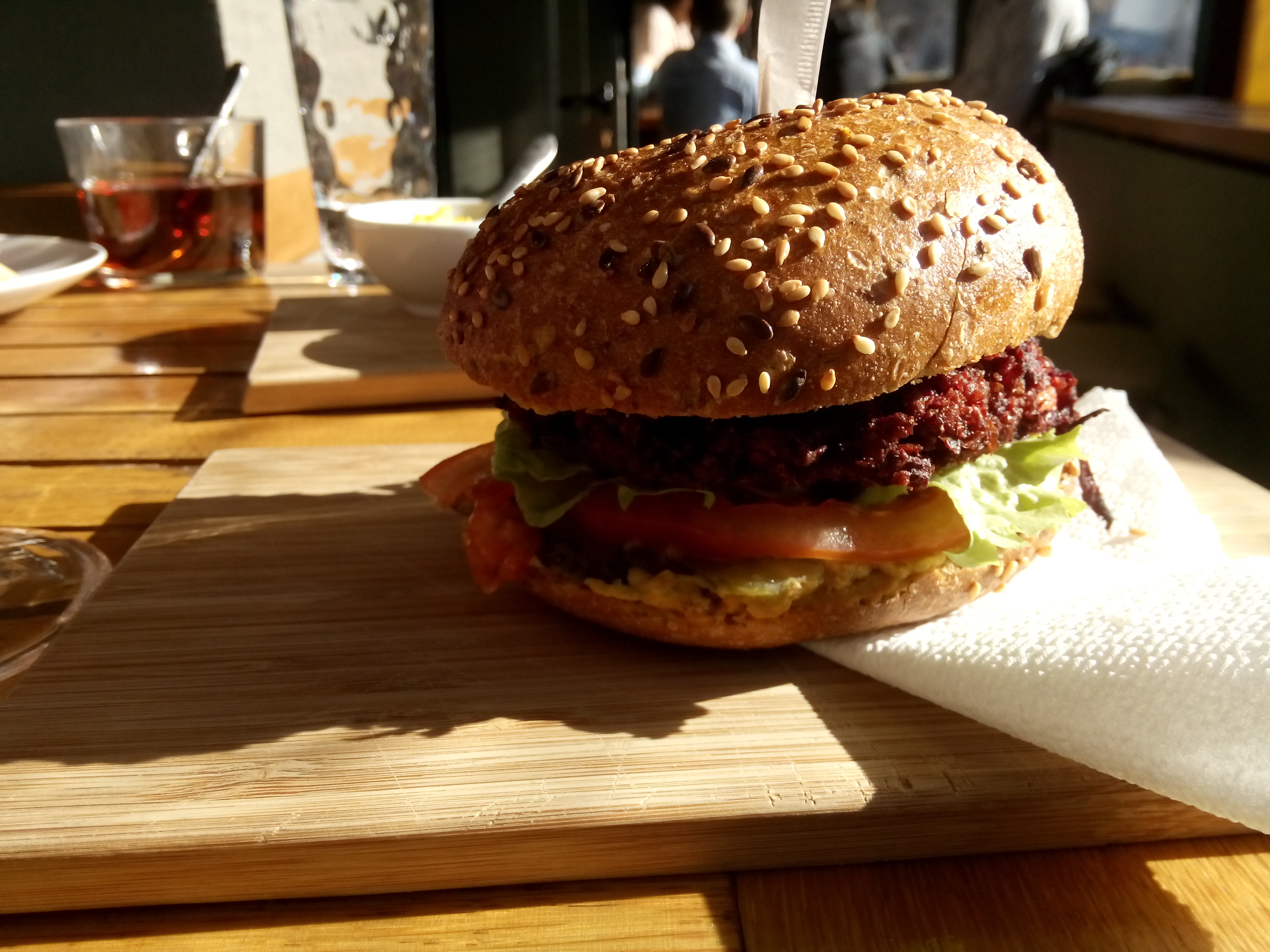 A purple burger in a seedy bun with salad on a wooden board