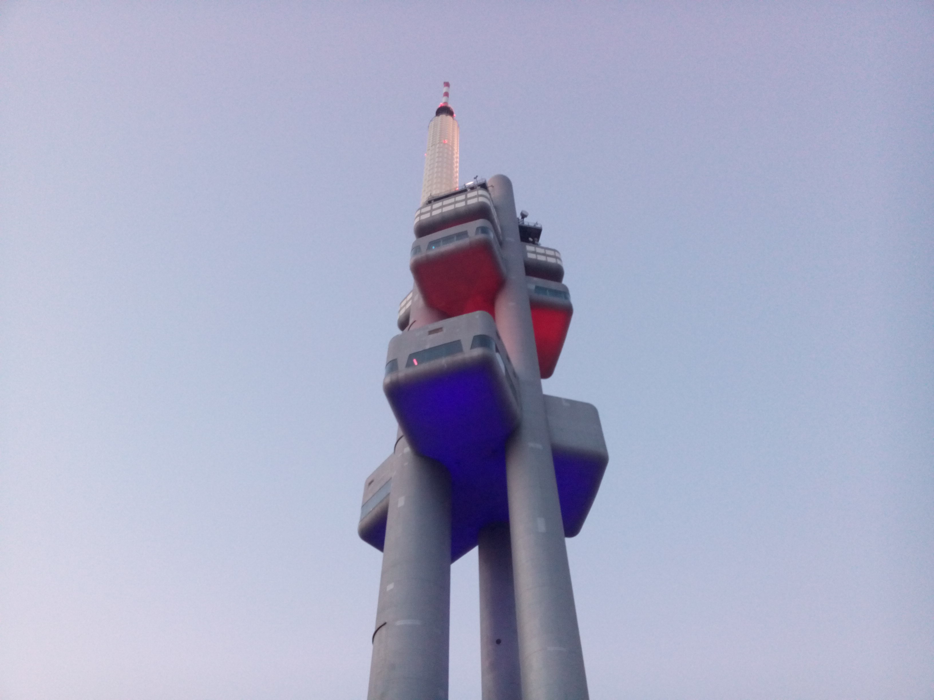 A white and red space-age looking tower against a pale blue evening sky