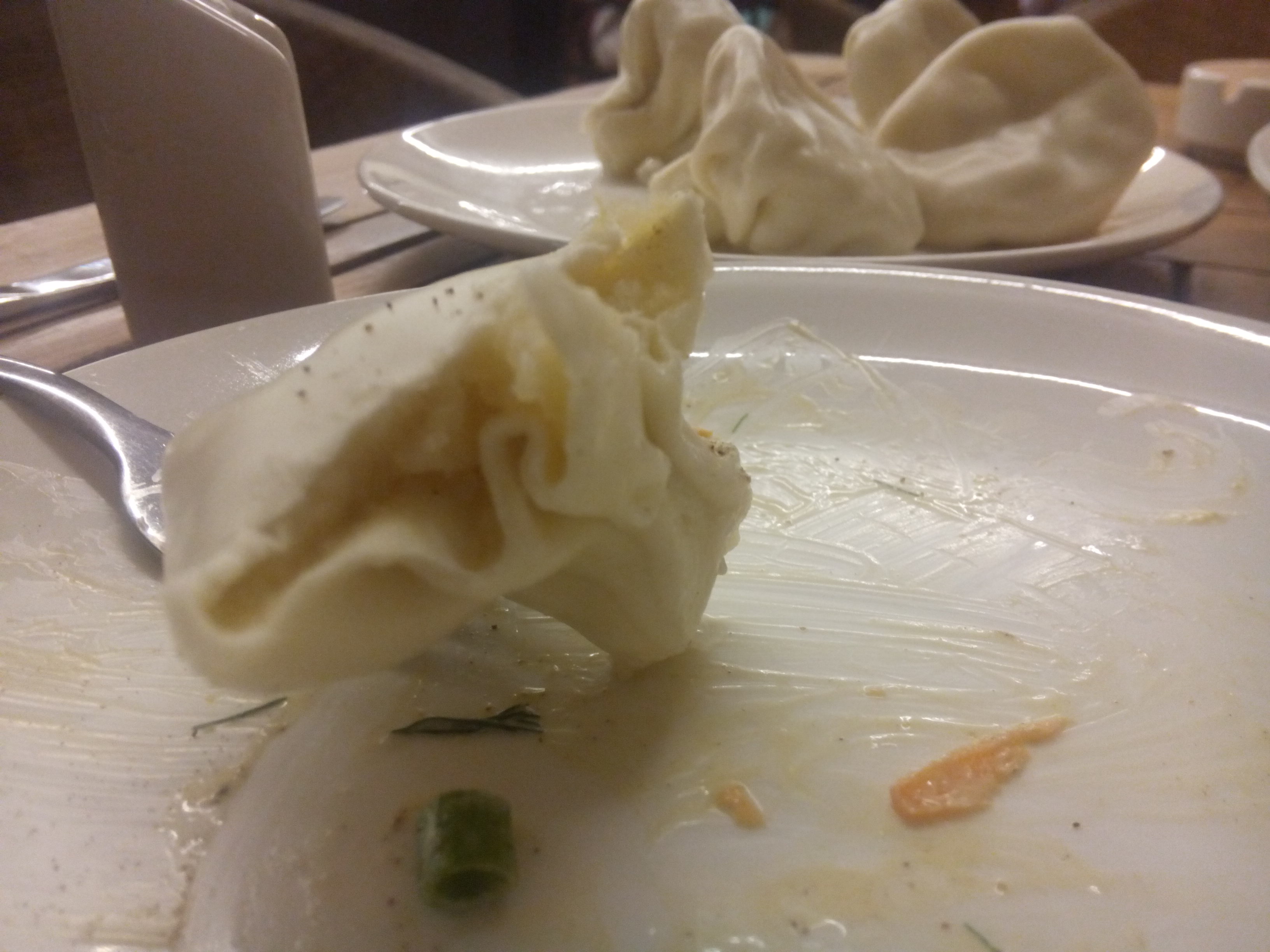 A half eaten dumpling with potato inside, and in the background more dumplings