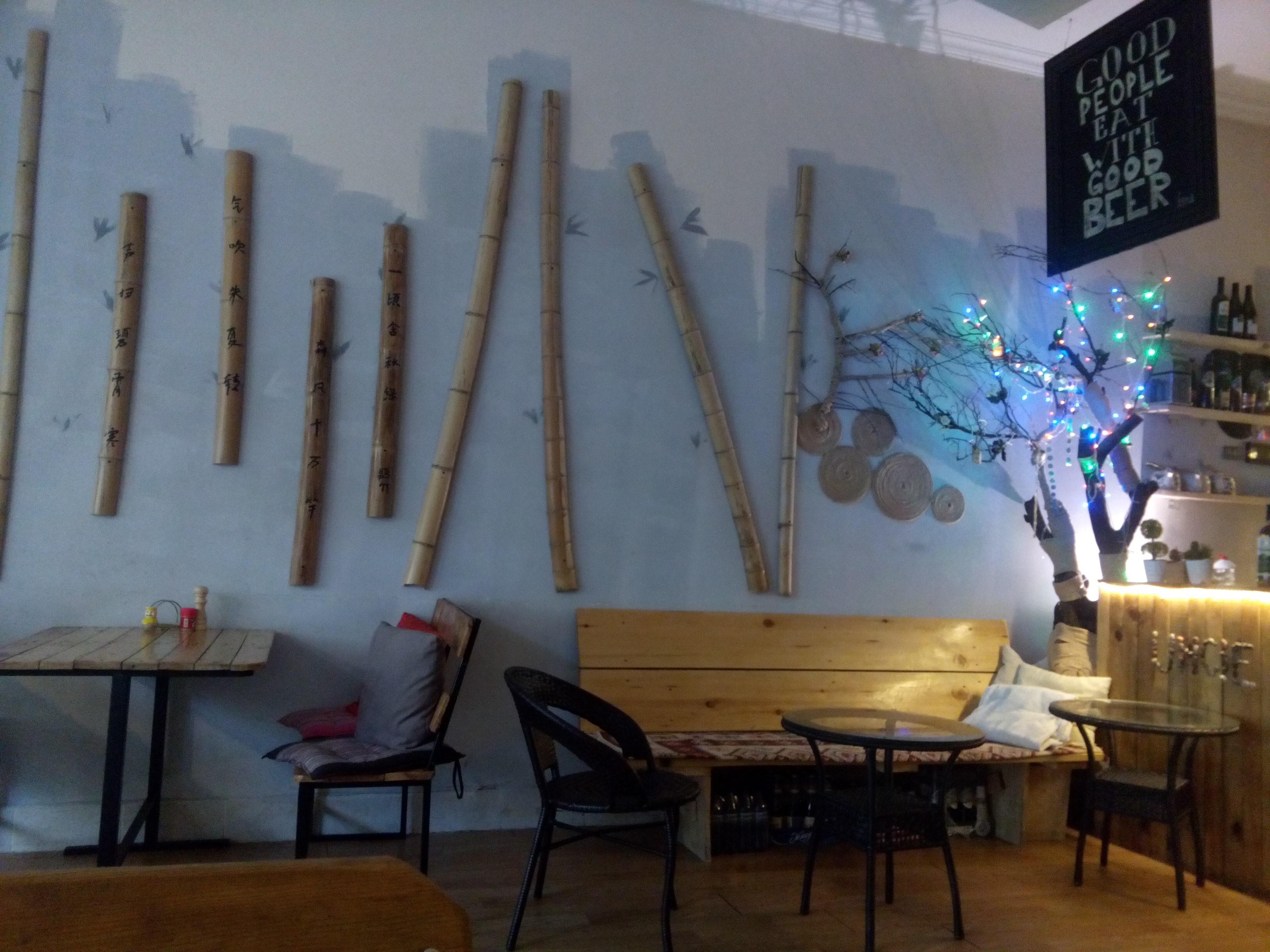 A restaurant interior, lots of bamboo decorating a blue wall, with wooden tables and chairs