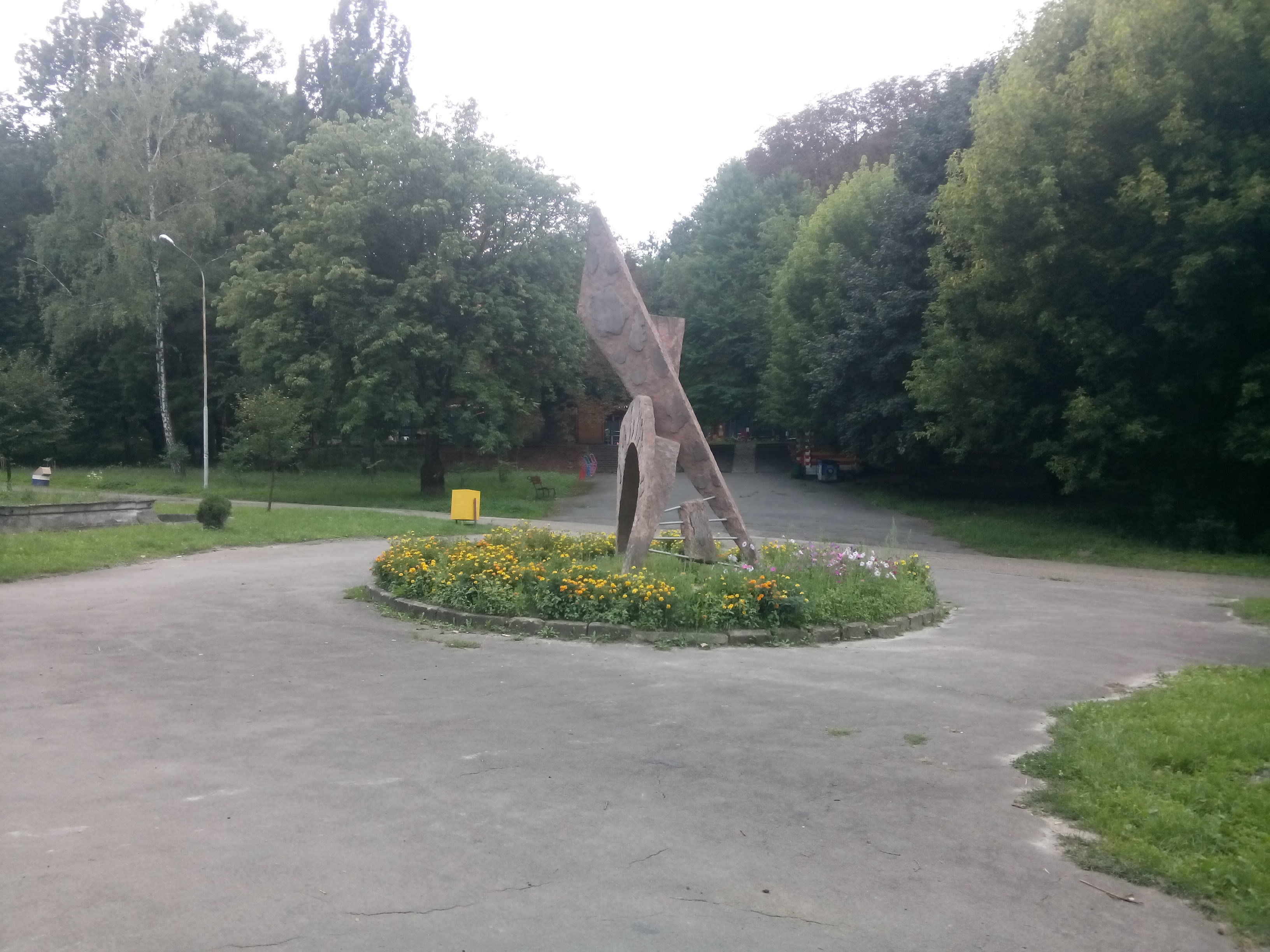 An abstract sculpture in the middle of a pedestrian roundabout, with trees in the background