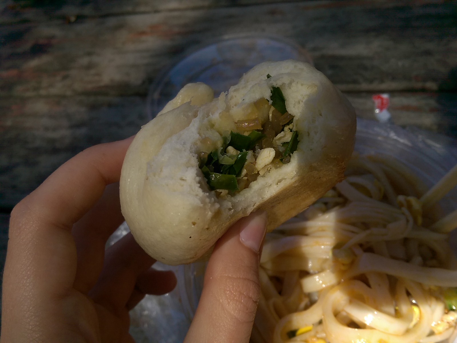 A hand holding a rice bun with a bite out