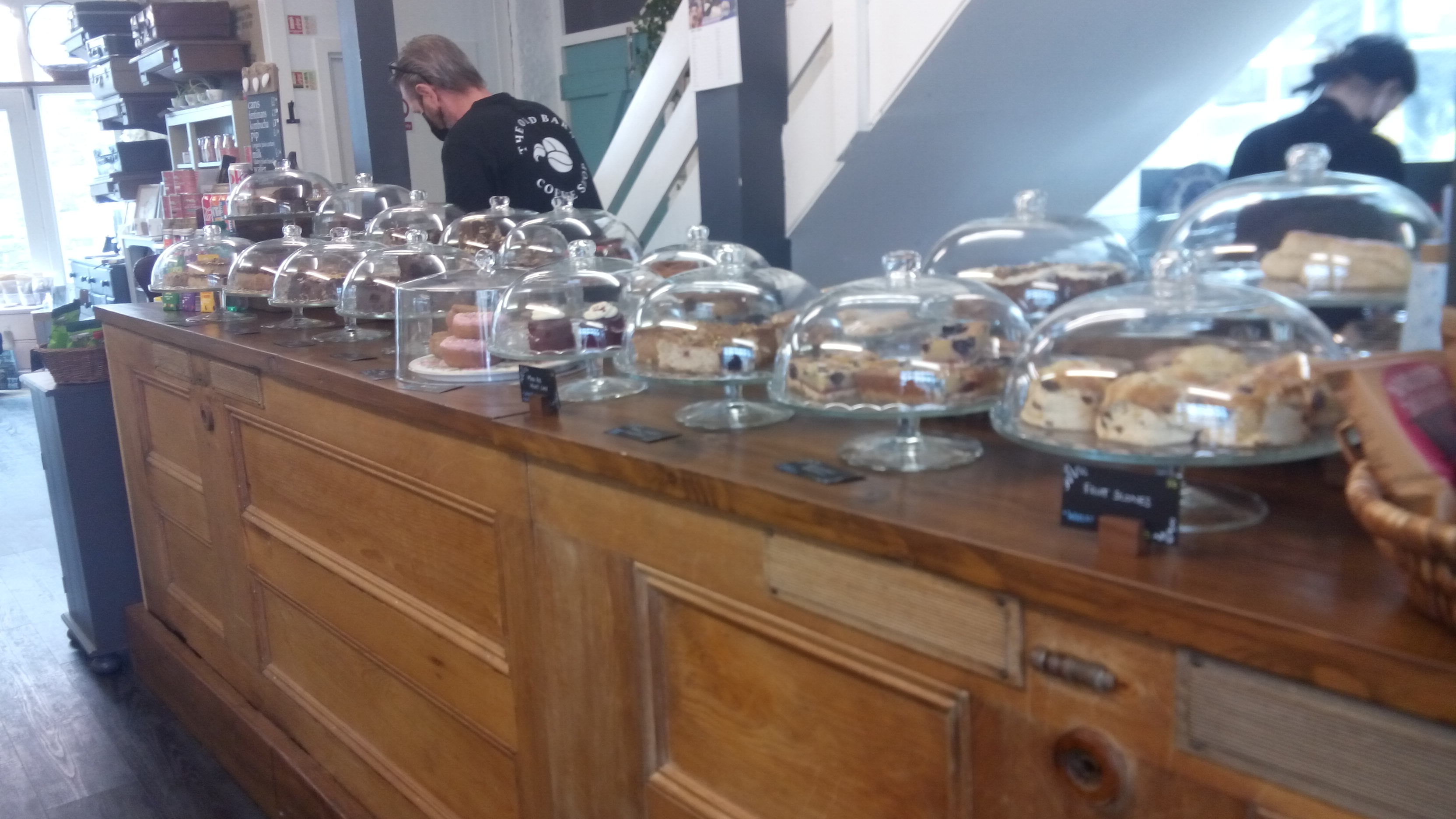 A wooden counter (made from old doors) supports an array of glass domes filled with cakes