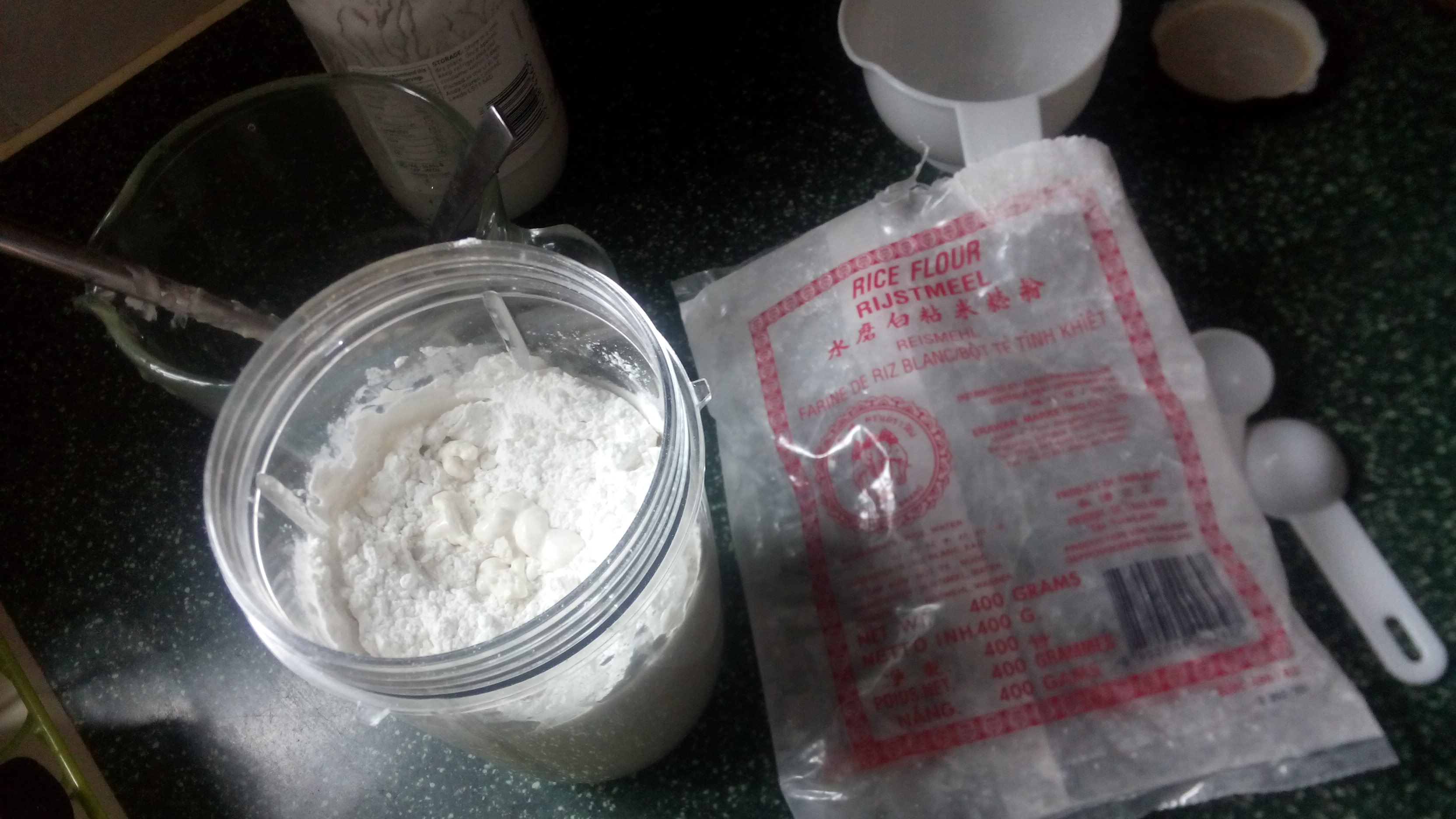 an empty rice flour bag beside a blender jug containing various white powders and liquids
